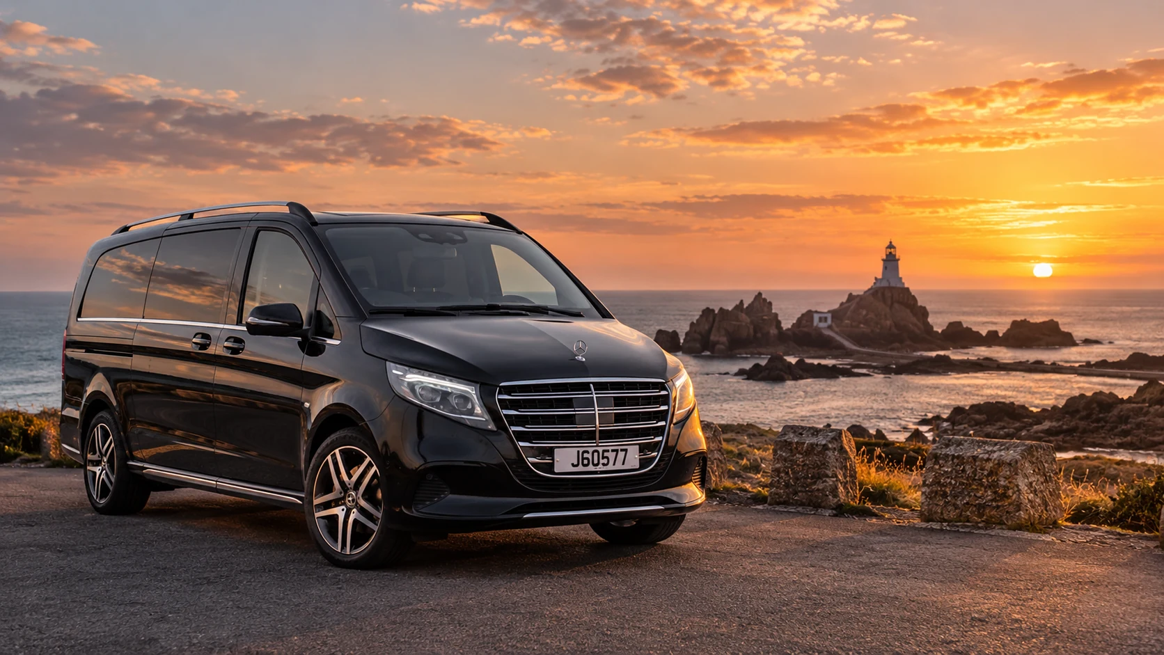 Black Mercedes V-Class overlooking La Corbière lighthouse at sunset in Jersey.